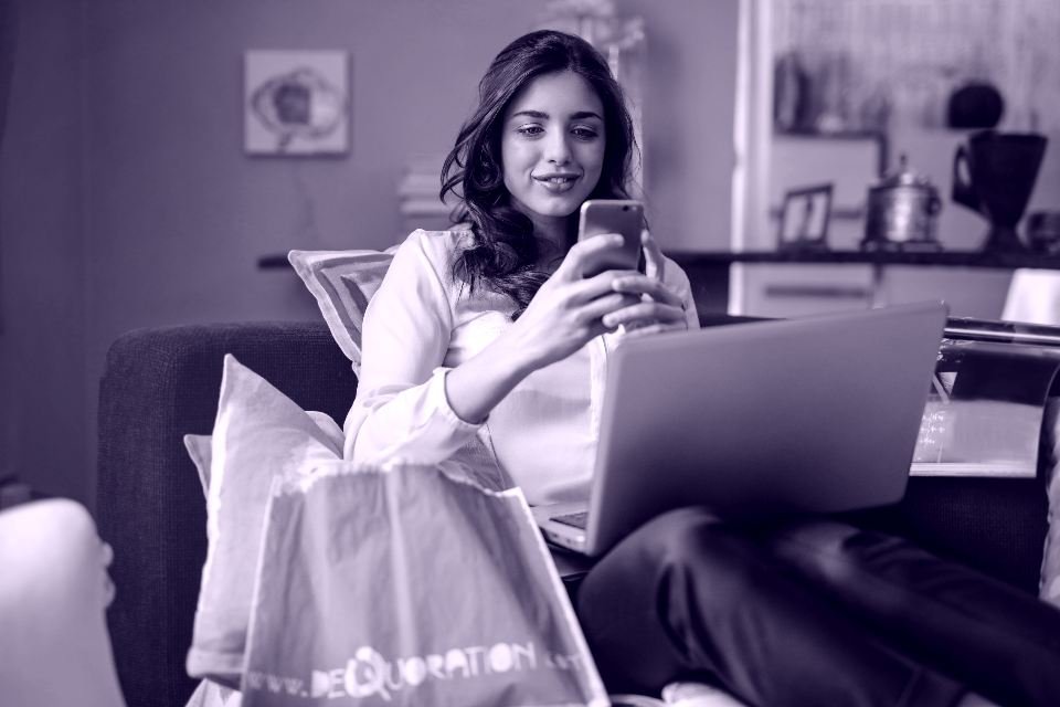 Clienta comprando desde el móvil y el portátil en el sofá