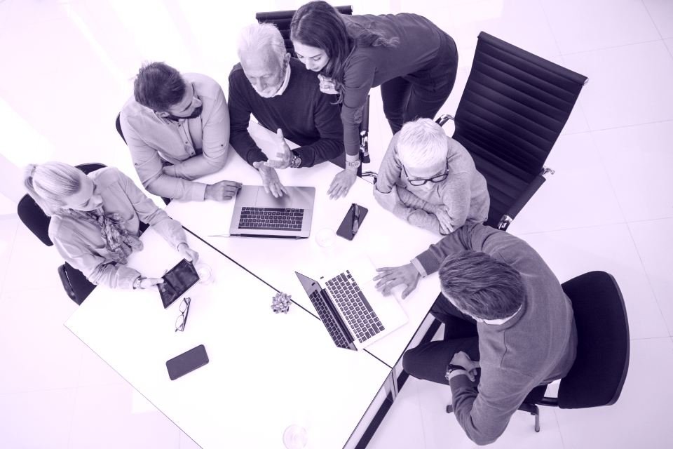 Equipo de trabajo reunido alrededor de una mesa con portátiles